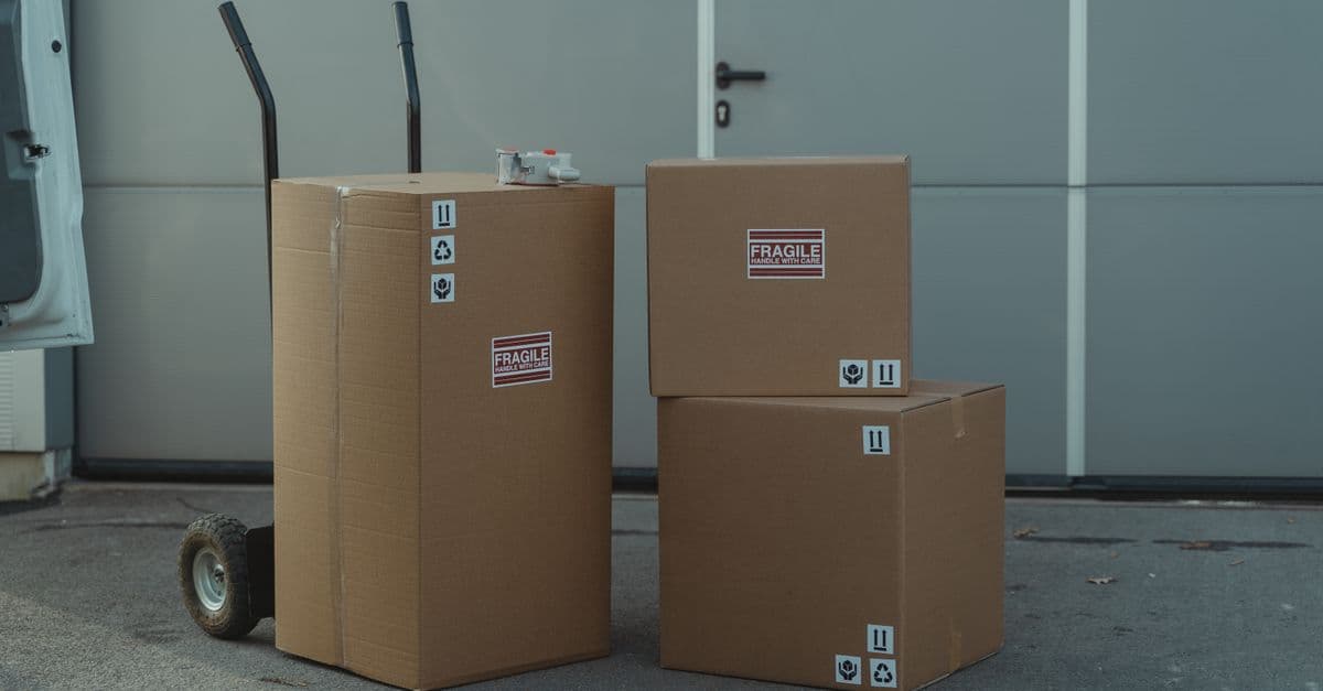 Kartons mit Versandetiketten auf einer Sackkarre vor einem Lagertor