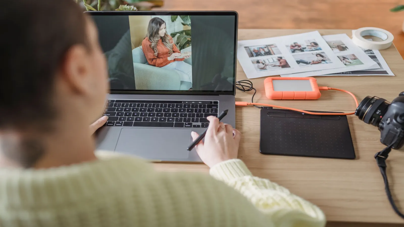 Person bearbeitet ein Porträtfoto am Laptop mit Grafiktablett und Kamera daneben — Symbolbild für die Kennzeichnung erzeugter und manipulierter Bildinhalte